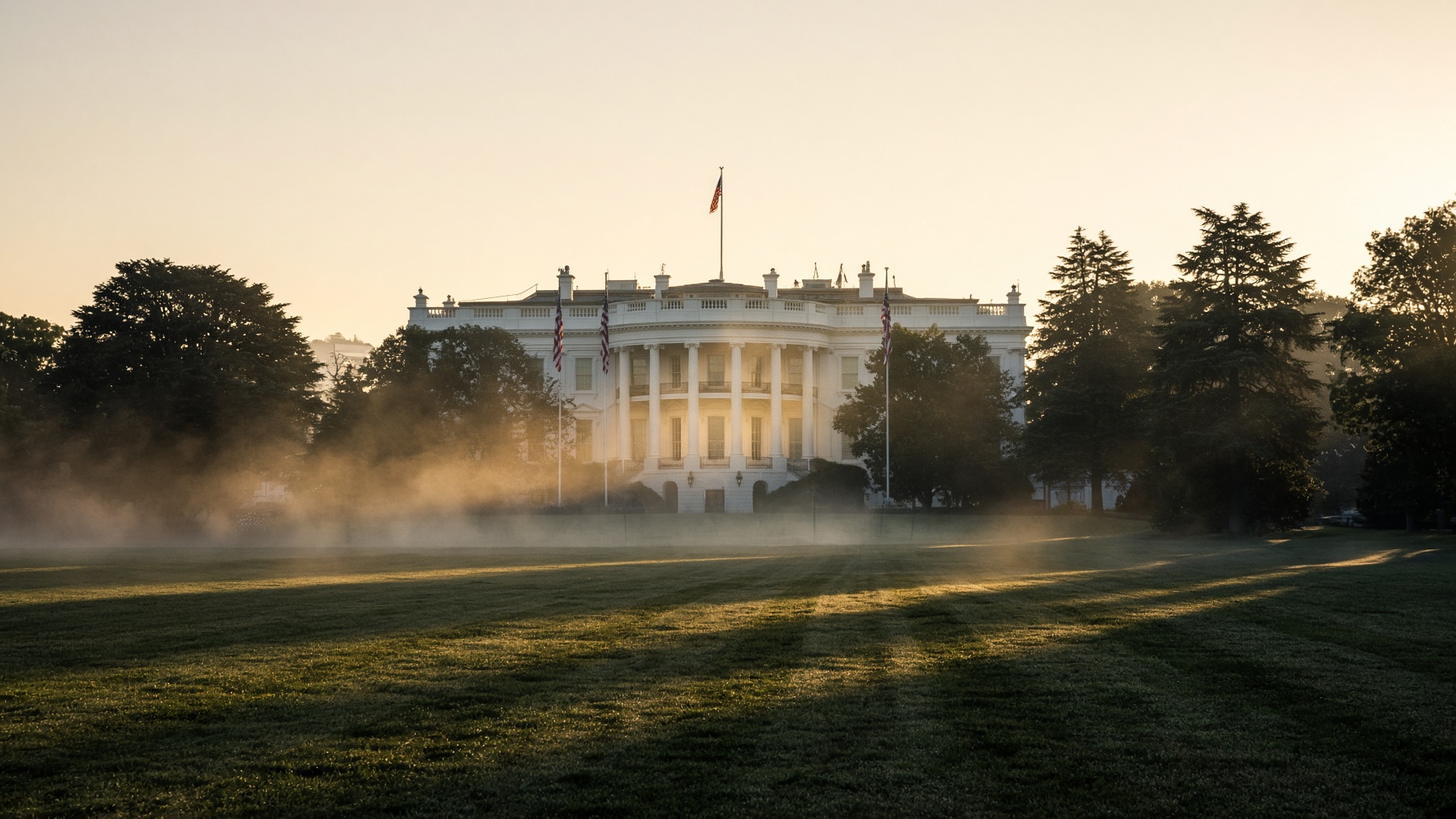 The White House at golden hour with flags and morning mist